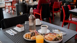A dining table with breakfast items, a bottle, and a cup of coffee. - Hotel Sommelier Agustinas (Santiago)