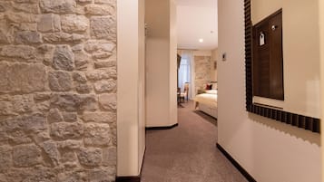 A hallway with stone walls, a bed, and a wooden door.