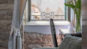 Una habitación con vista a un edificio histórico a través de una ventana con barandilla de metal.