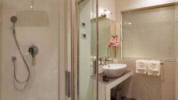 A modern bathroom with a glass-enclosed shower, a sink, and a mirror.