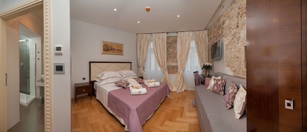 A bedroom with a bed, a bedside table, a TV mounted on the wall, and a shower area. - Heritage Hotel Antique Split (Split)