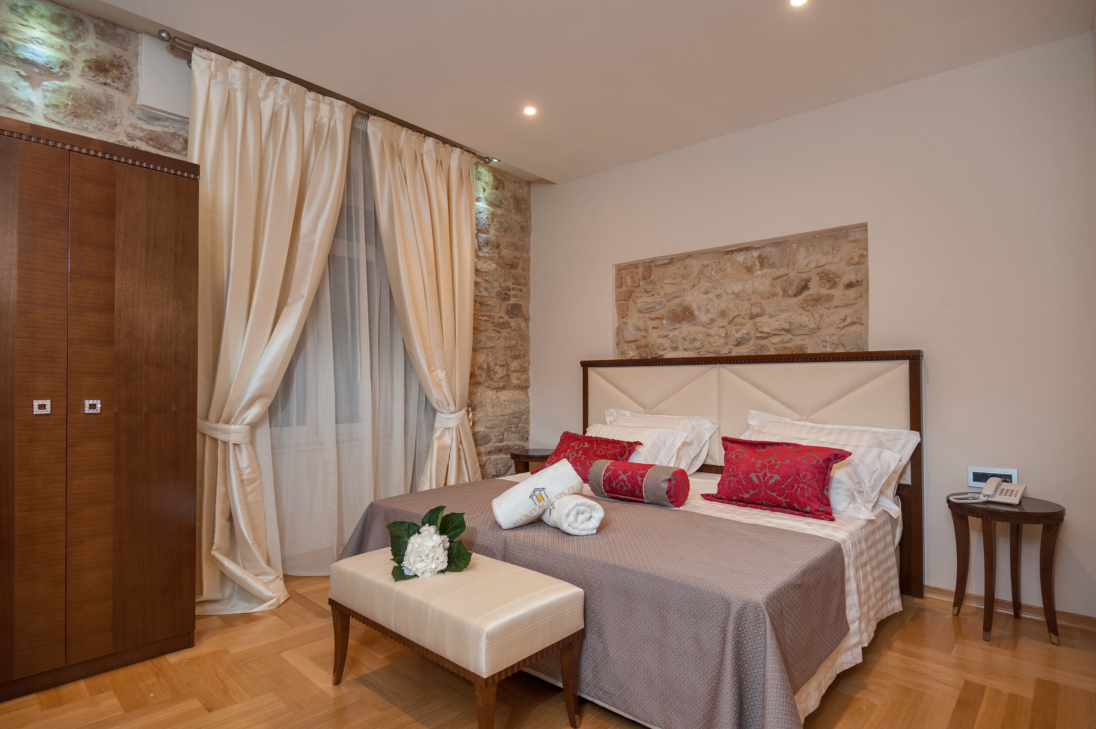 A neatly arranged bedroom with a bed, a bench, a bedside table, and a wardrobe.
