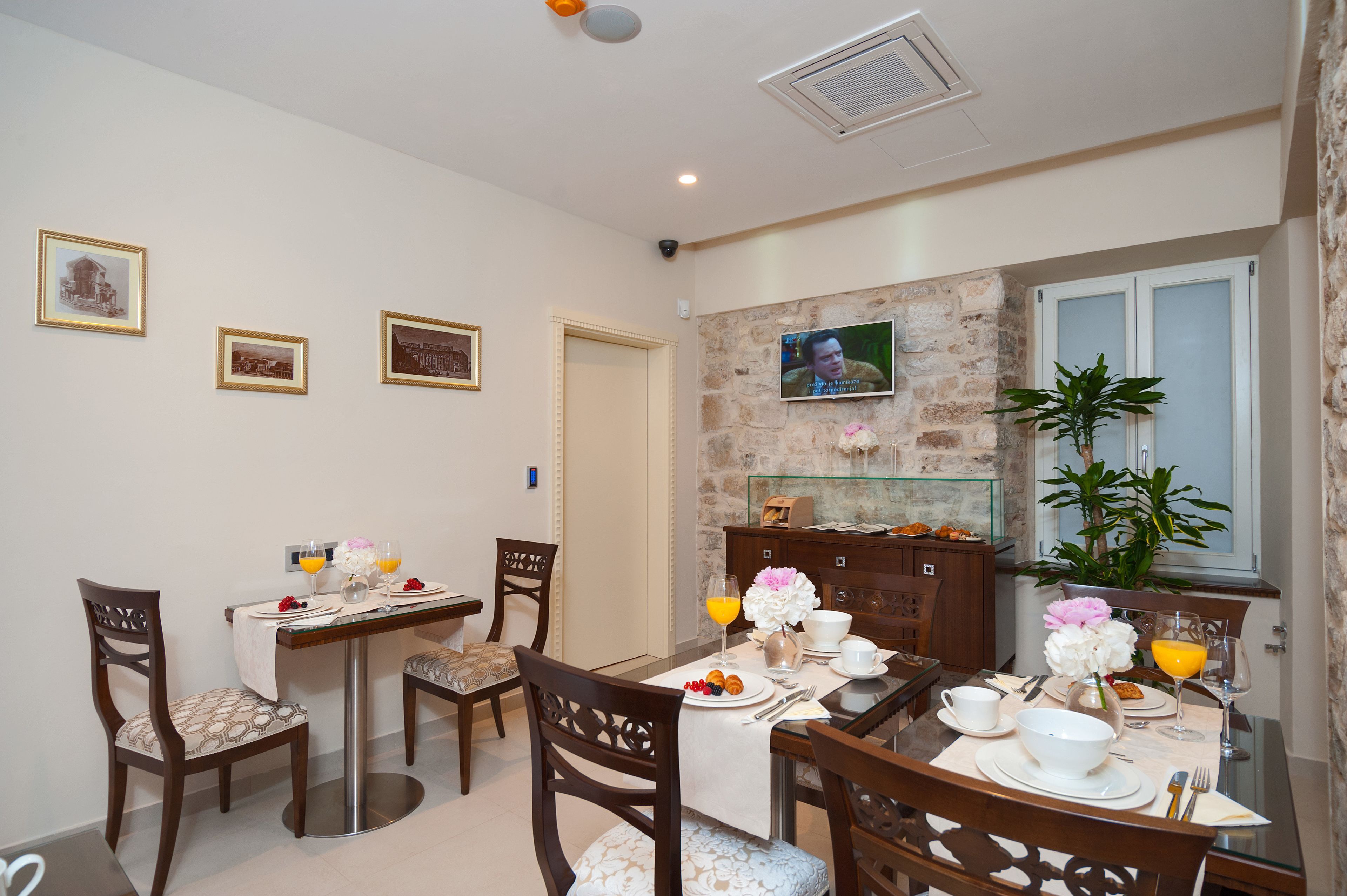 Comedor con pared de piedra, televisor sobre la mesa y planta en maceta.