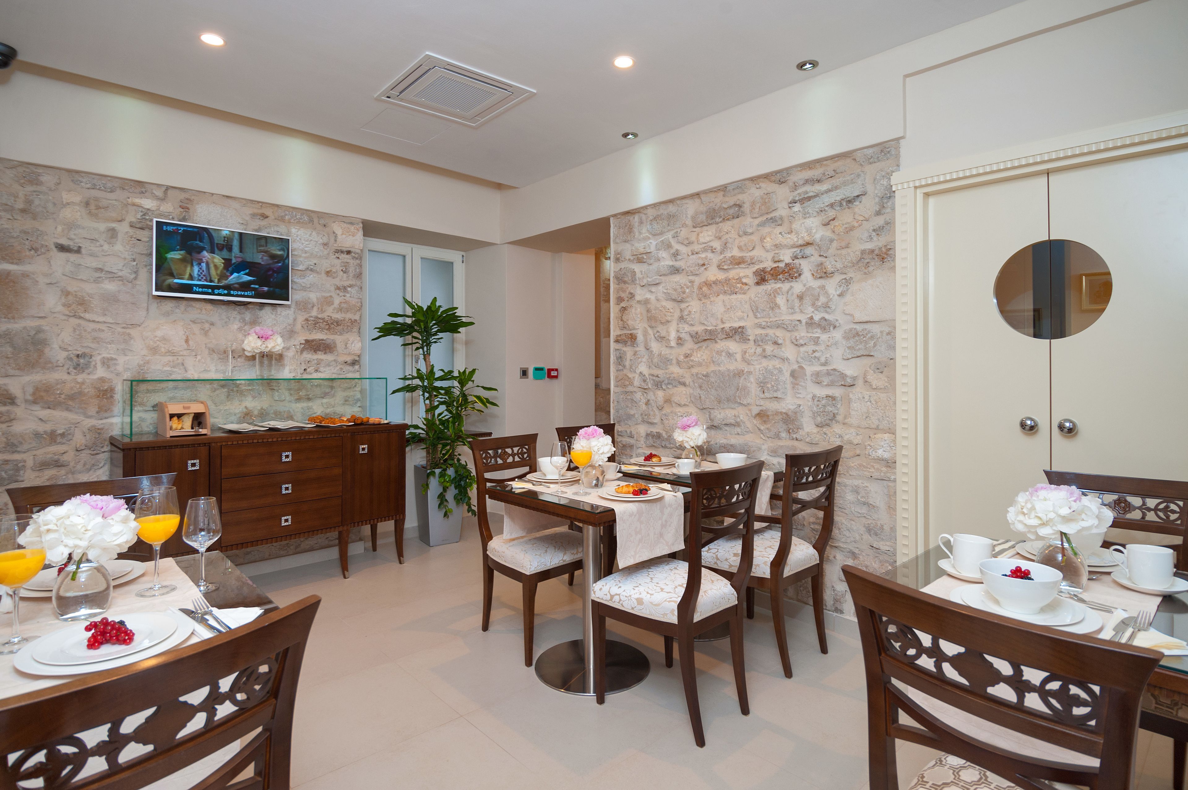 Un comedor con paredes de piedra, muebles de madera y un televisor montado en la pared.