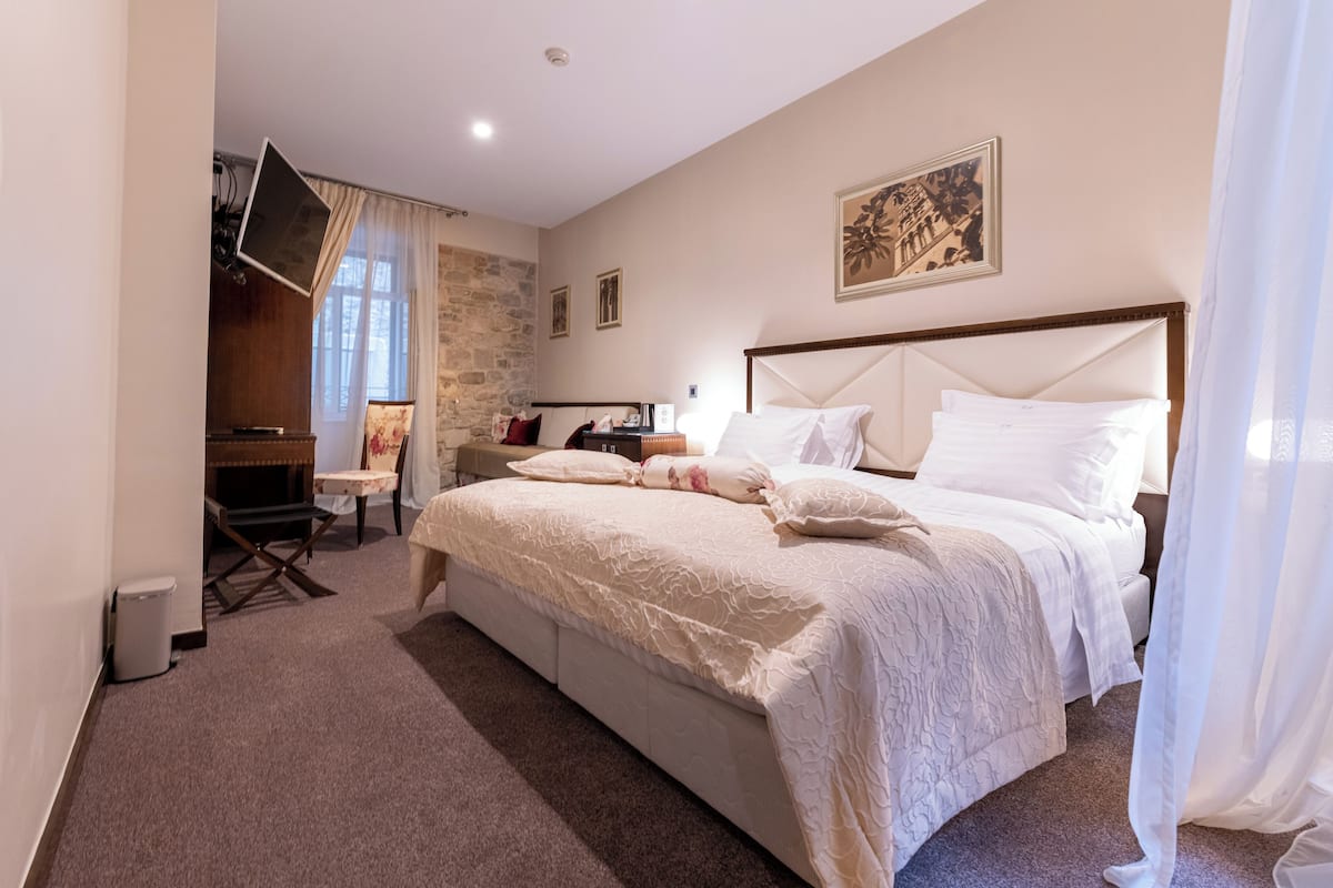 A hotel room with a large bed, a desk, a chair, and a television.