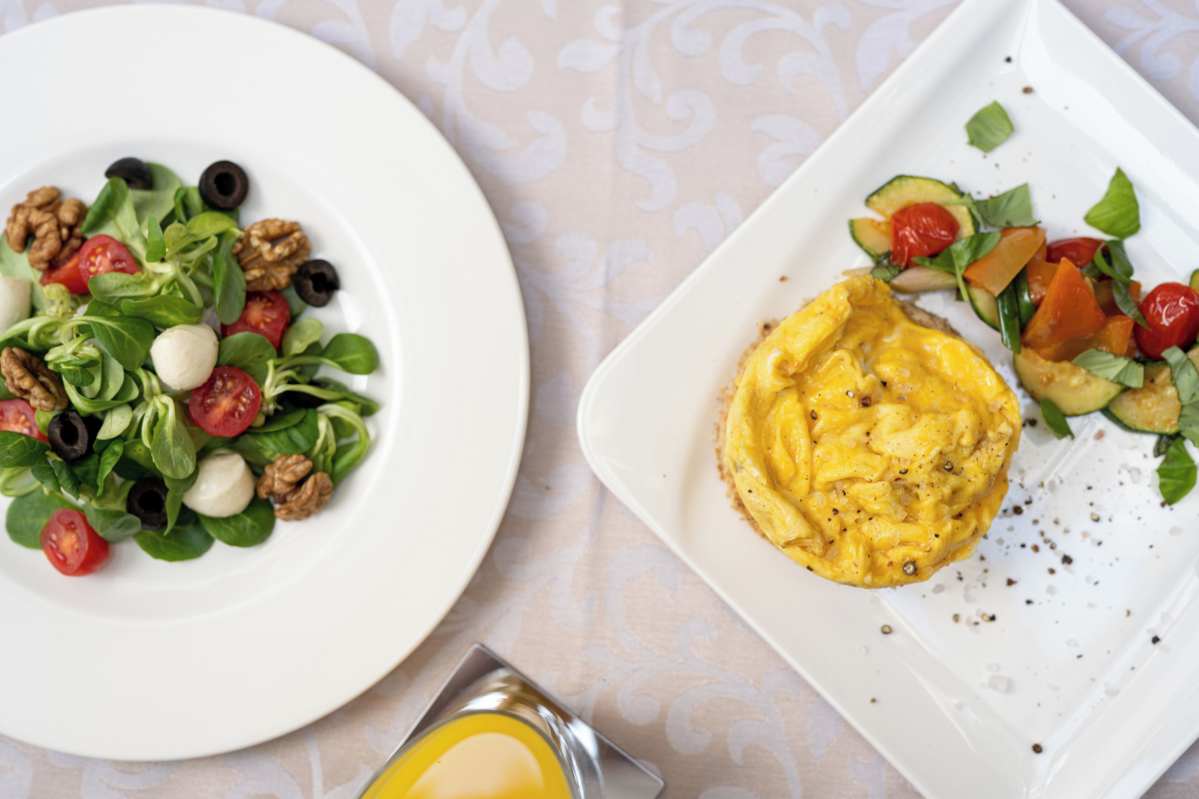 Zwei Teller Essen, einer mit Salat und der andere mit Rührei und Gemüse.
