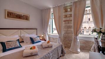 A hotel room with a large bed, a view of a historic building, and a stone wall.