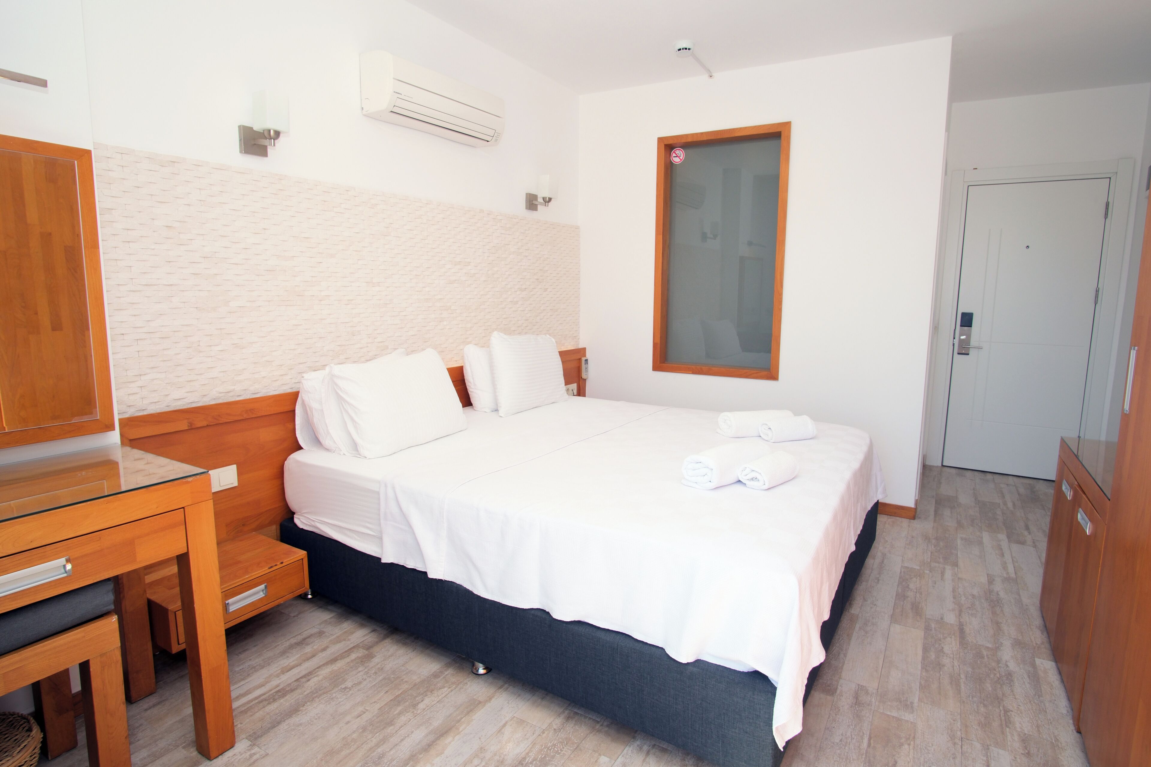 A hotel room with a wooden bed, a desk, and a wardrobe.