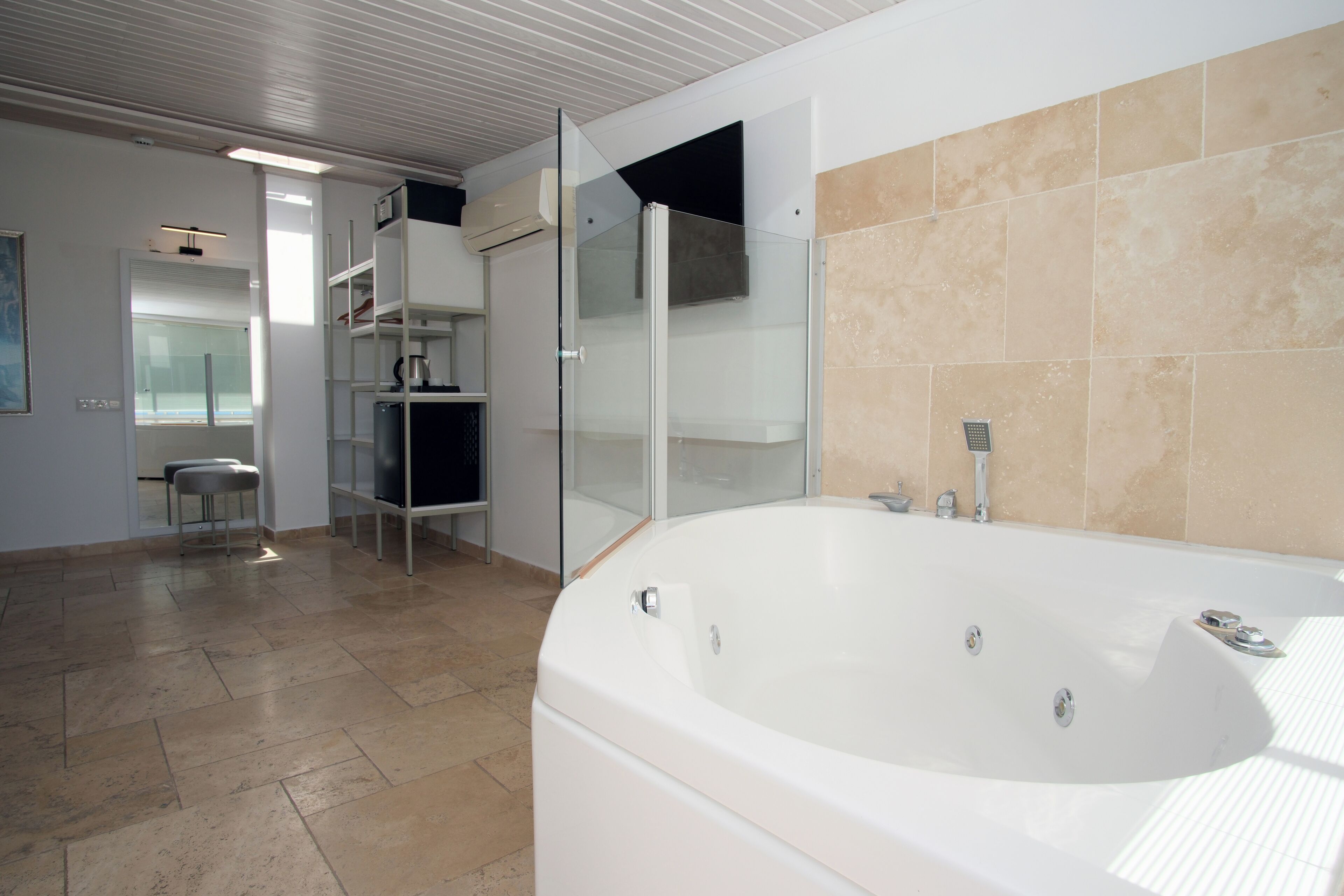 A modern bathroom with a large bathtub, glass shower enclosure, and a tiled floor.