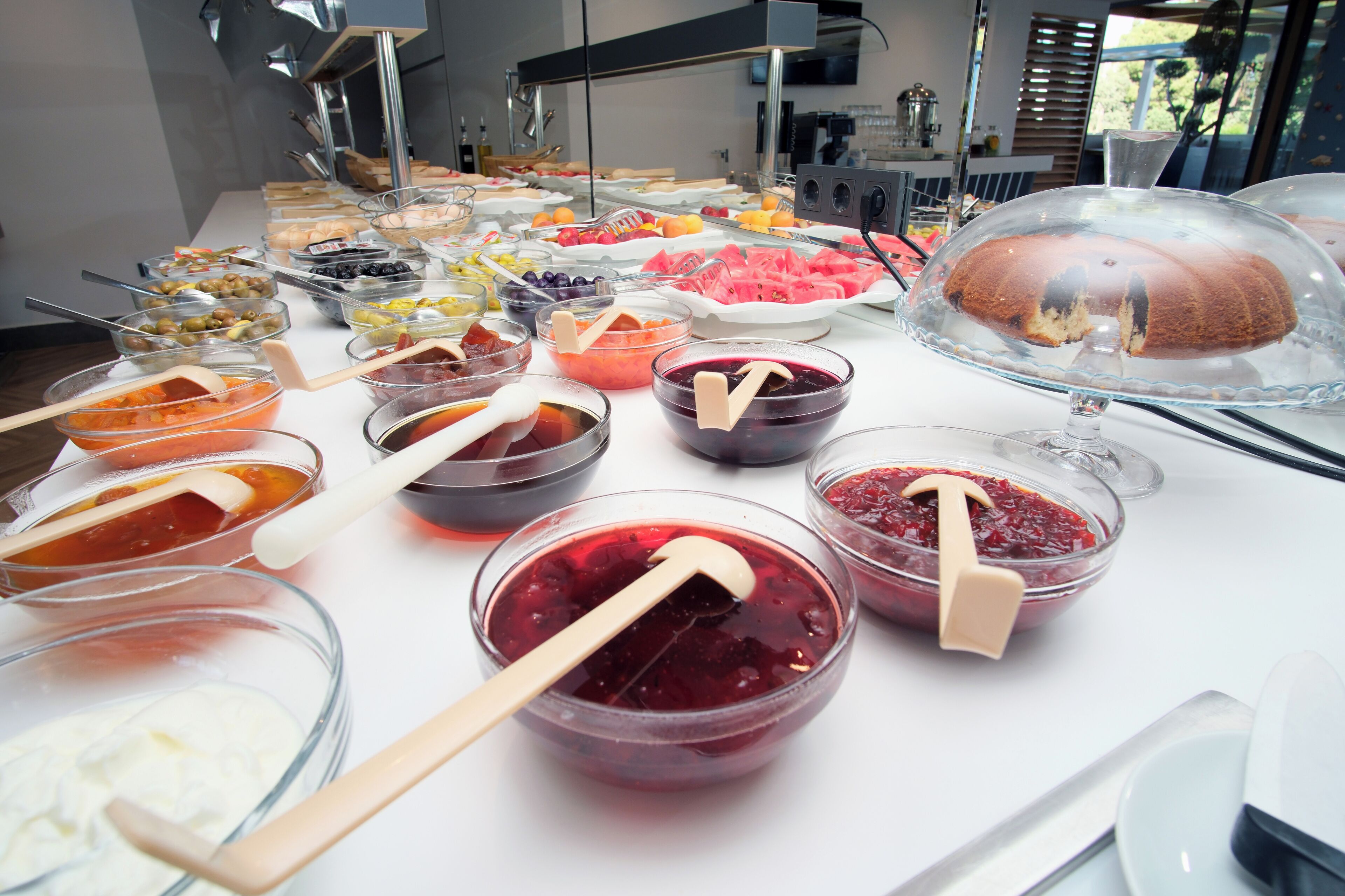 A buffet with various food items and a covered dessert display.