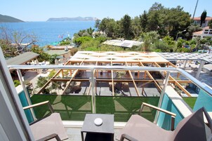 Una terraza en la azotea con vista al mar, rodeada de vegetación y edificios.