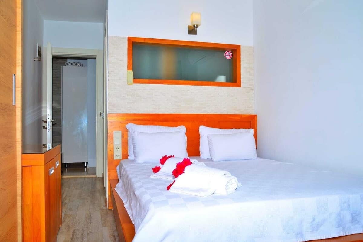 Ein Hotelzimmer mit einem Bett, einem Holzschrank, einer Tür und einer Wandleuchte.