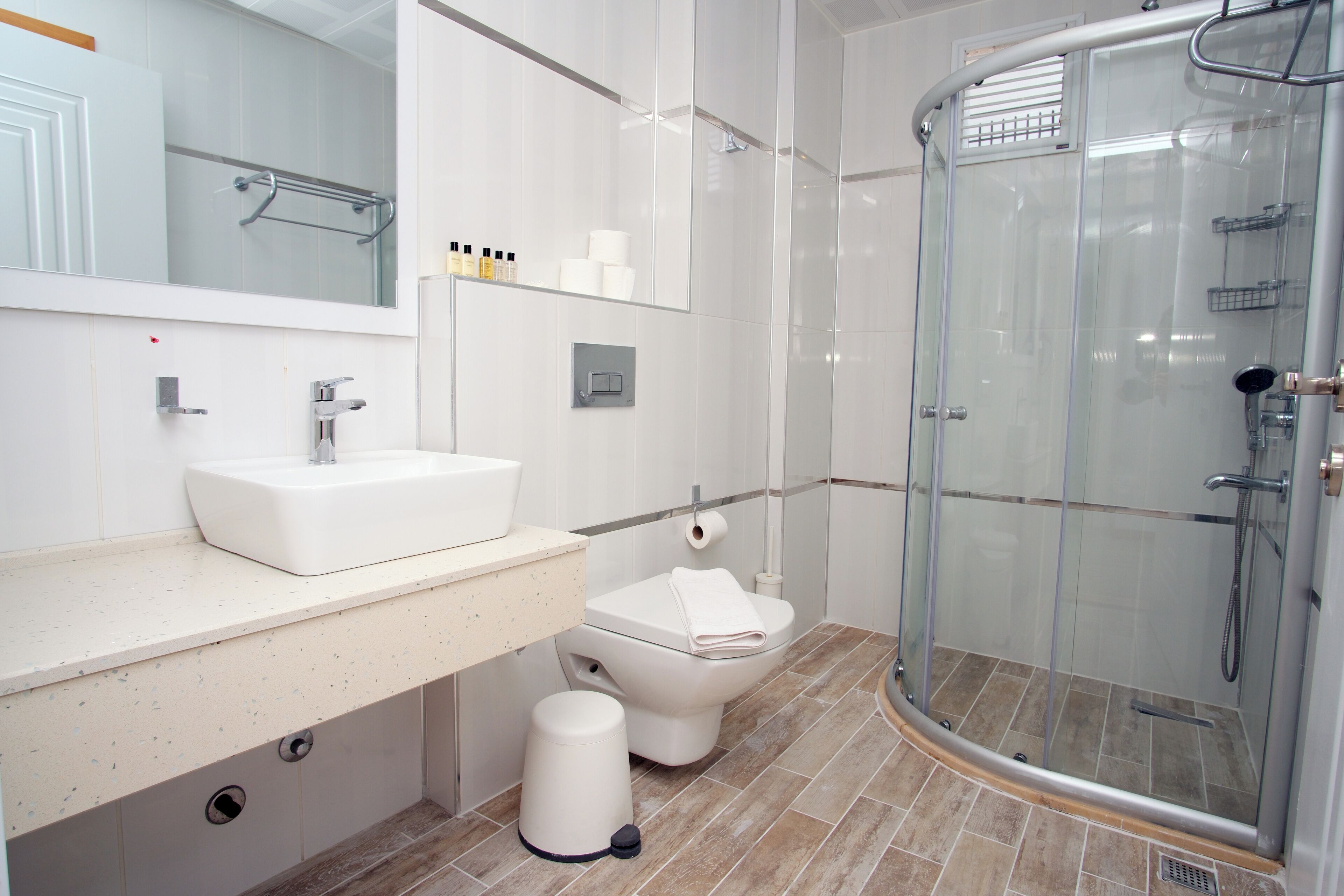 A modern bathroom with a white sink, toilet, and glass-enclosed shower.