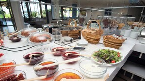 Buffet com diversos pratos, incluindo saladas, frutas e pães.