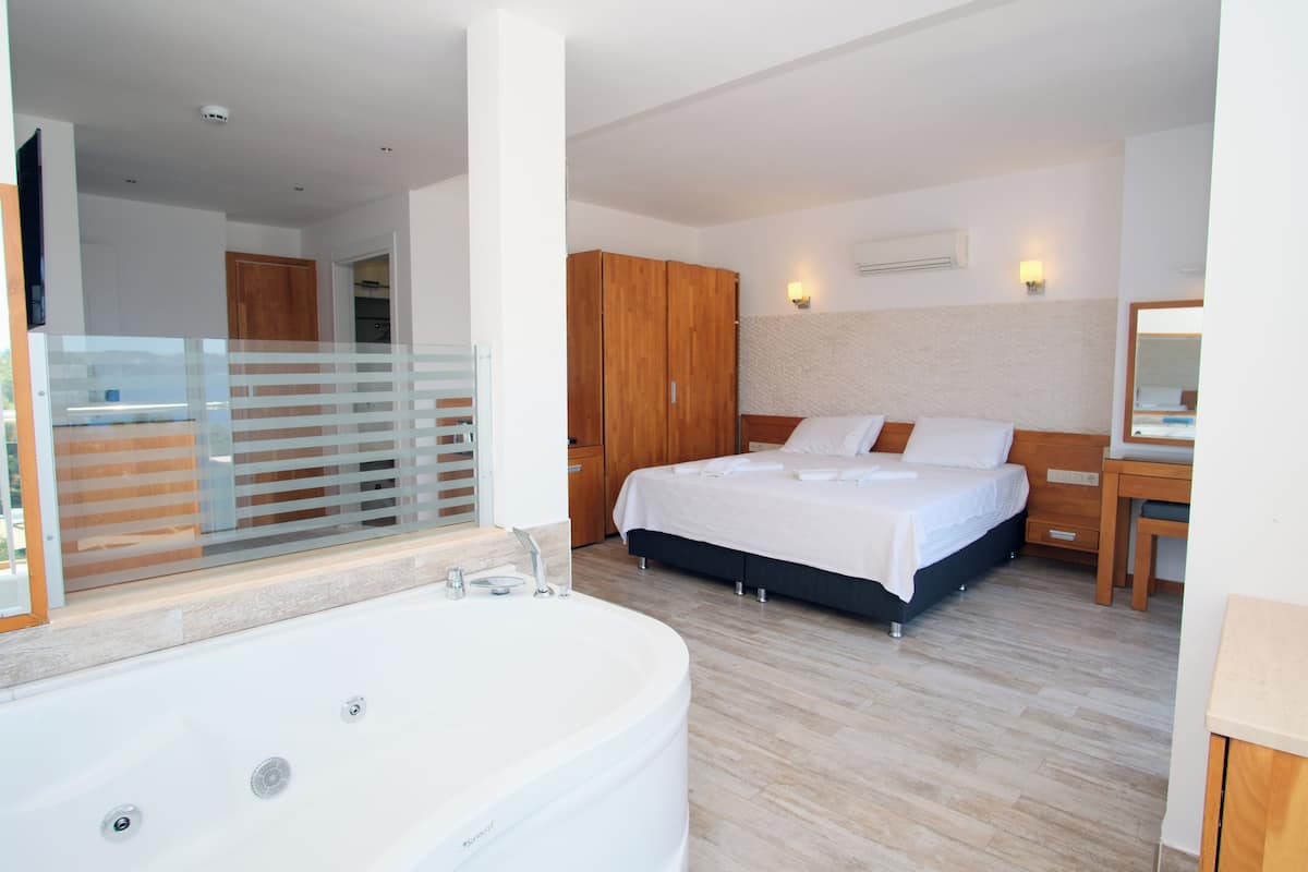 Ein modernes Schlafzimmer mit einem großen Bett, einem Holzschrank, einem Badezimmer mit Badewanne und einem großen Spiegel.