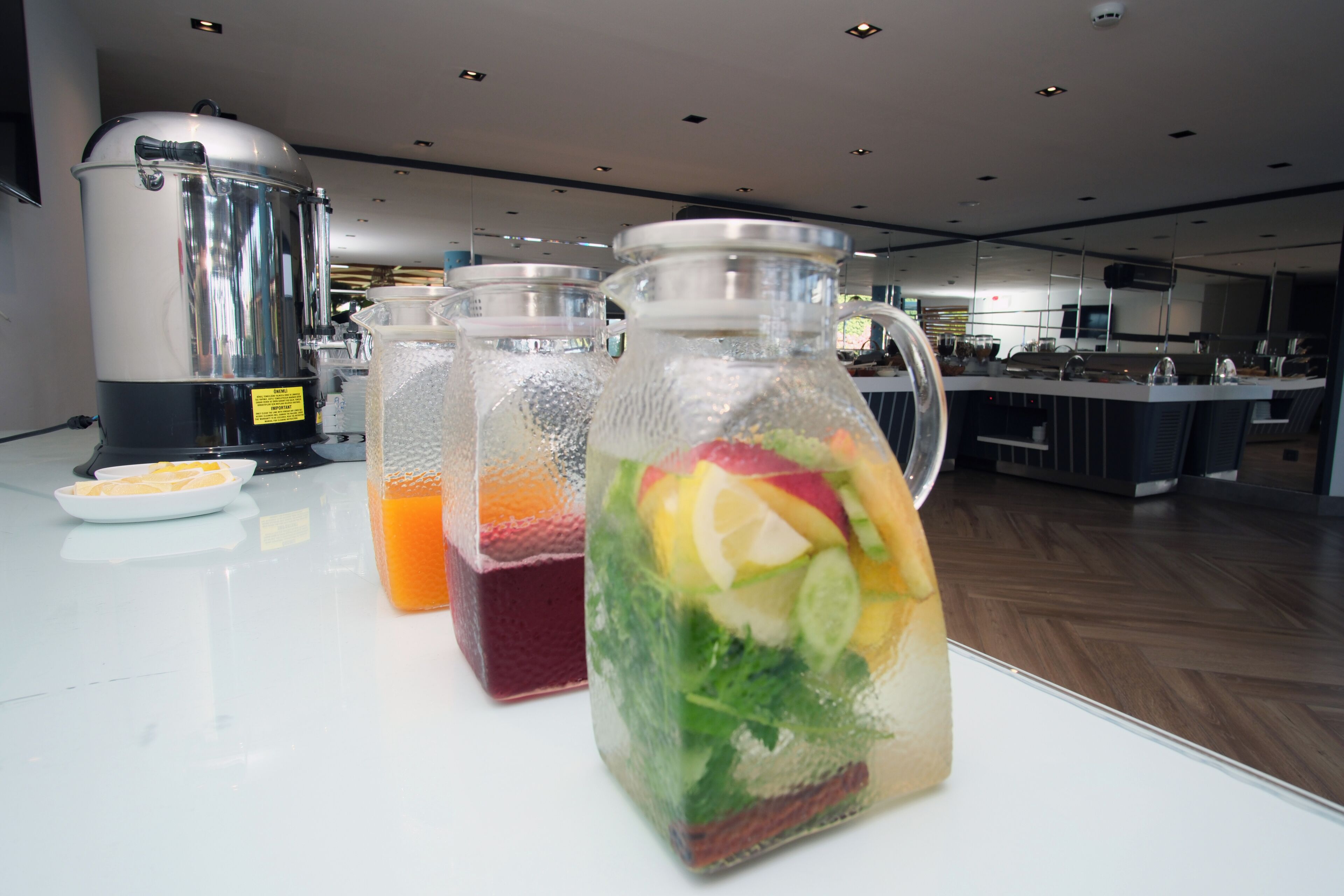 A kitchen area with a coffee maker, two glass containers with fruit, and a plate with lemon slices.