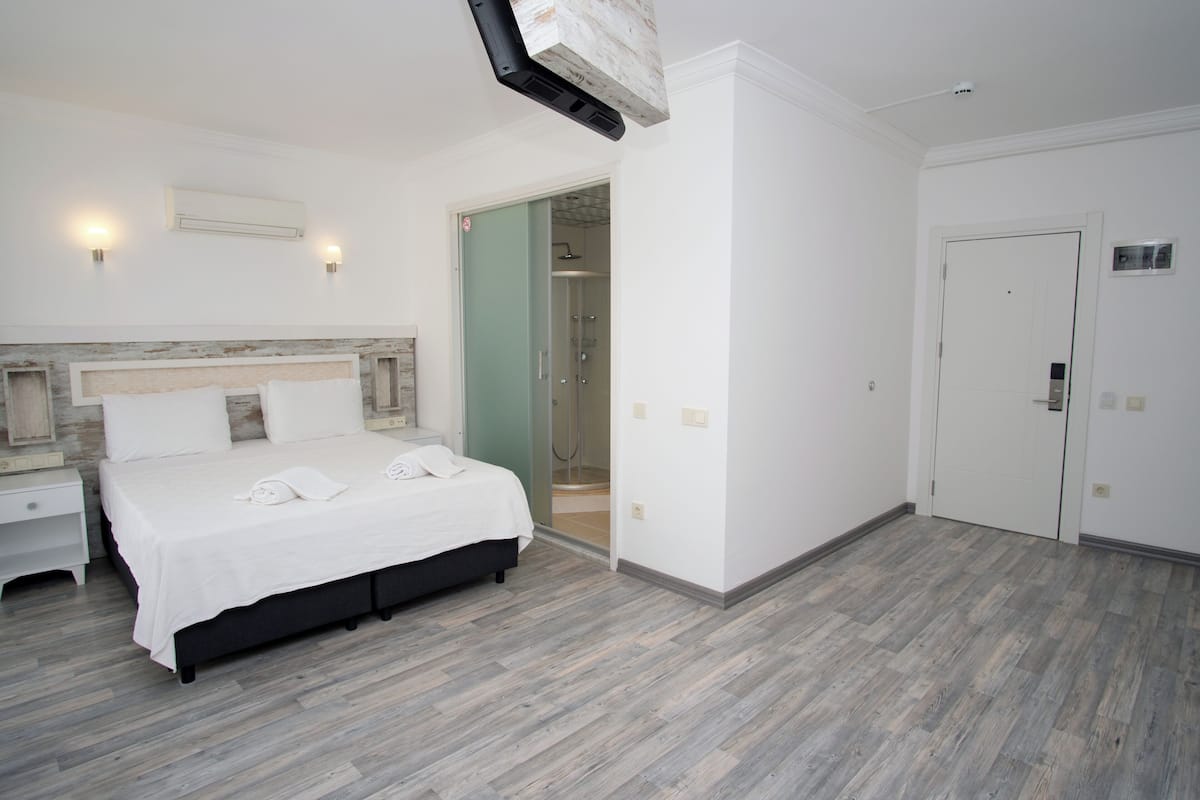 Ein Schlafzimmer mit Bett, Nachttischen, einem begehbaren Kleiderschrank und einer Dusche.