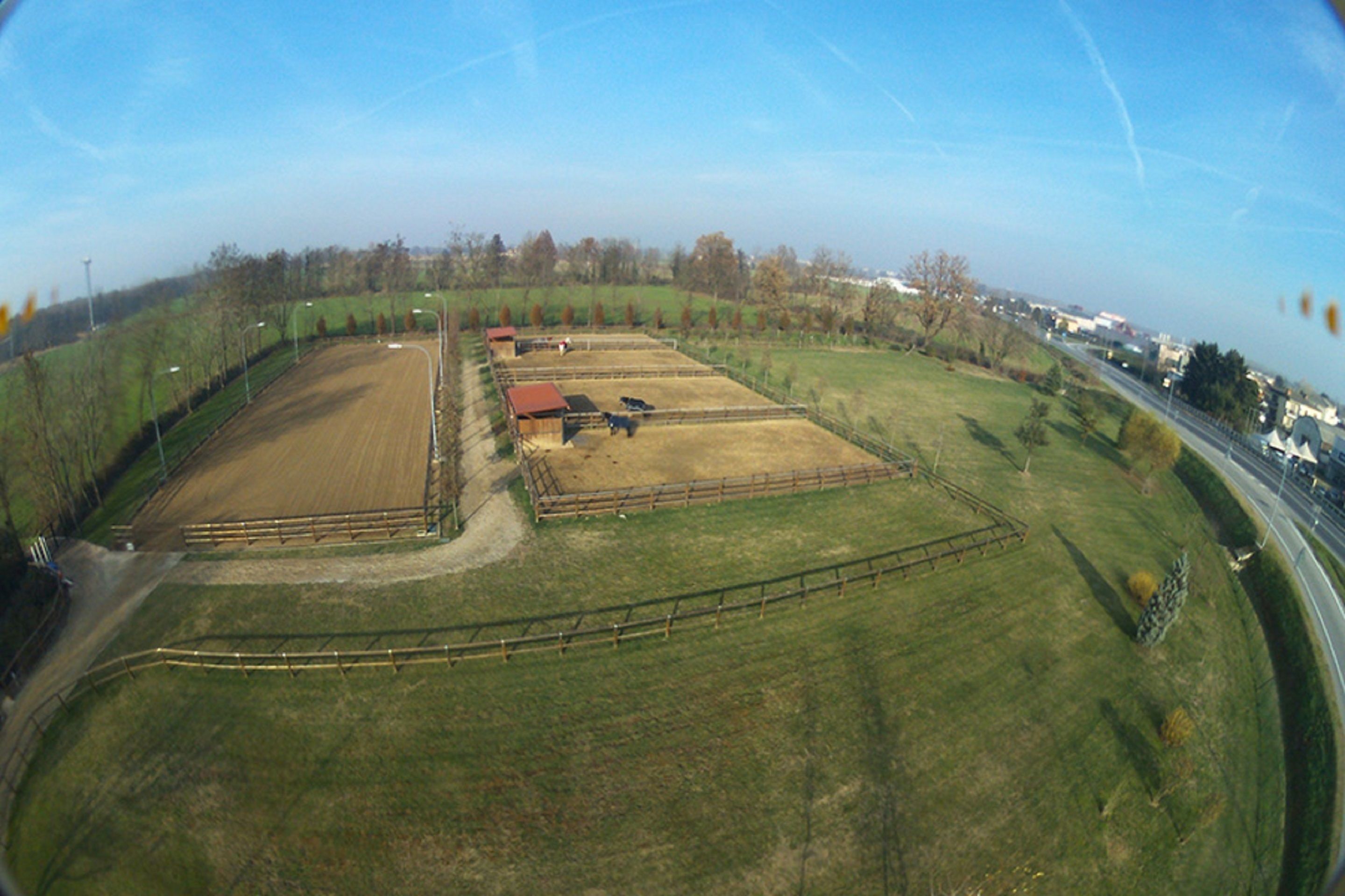 A large, fenced property with multiple buildings and open fields.