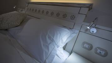 Ein ordentlich bezogenes Bett mit weißen Leinen, ein Kopfteil mit floralen Ausschnitten und Nachttischlampen.