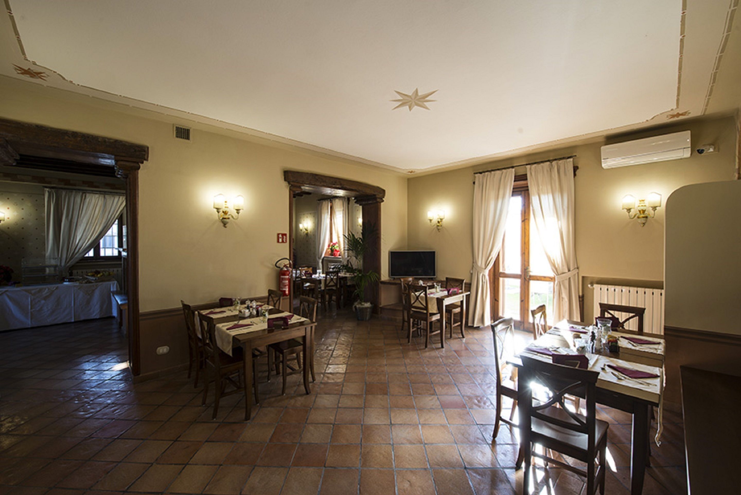 Un comedor amplio con varias mesas y sillas, un televisor y una chimenea.