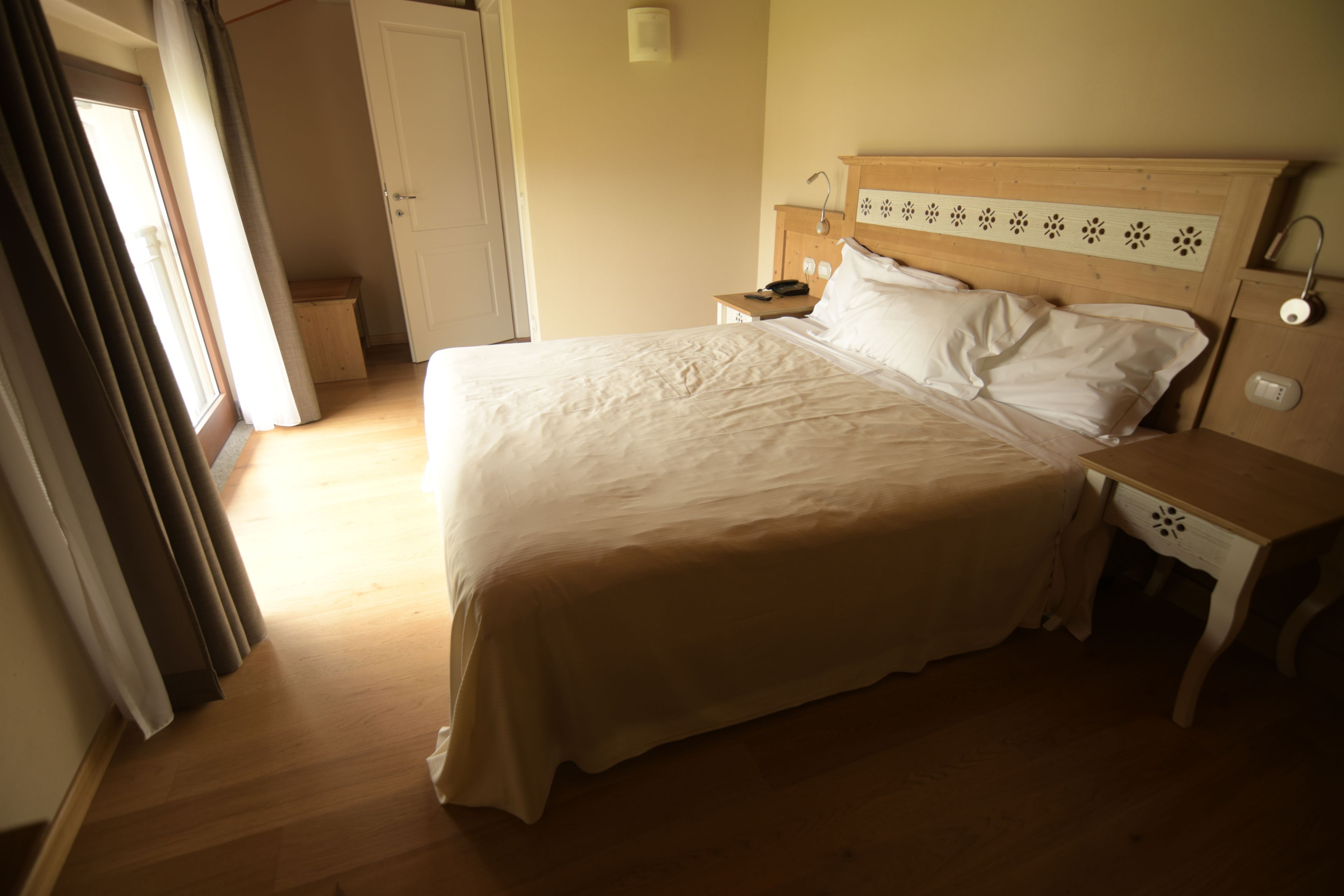 A bedroom with a large bed, wooden headboard, bedside tables, and a nightstand.