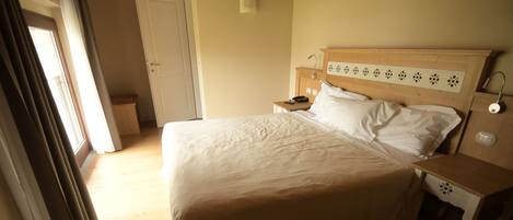 A bedroom with a large bed, wooden headboard, bedside tables, and a nightstand.