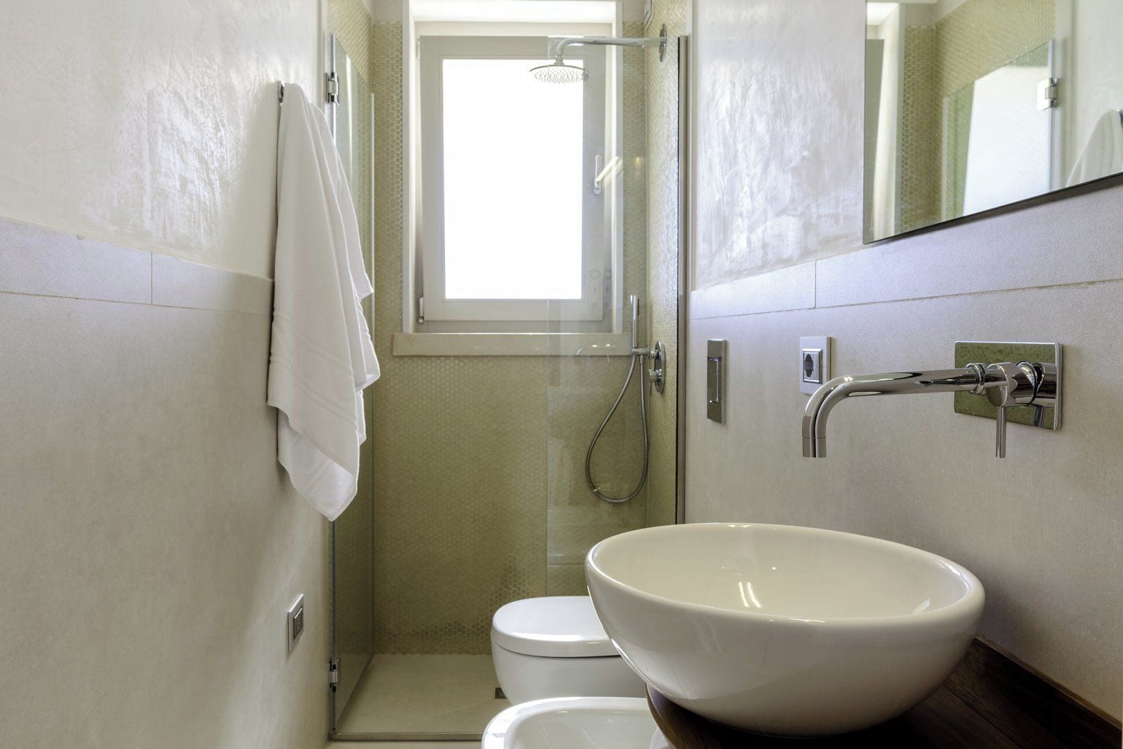 A small bathroom with a white sink, a toilet, and a shower.