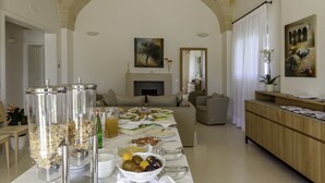 Un comedor con mesas de buffet, incluyendo recipientes de comida, un frutero y un dispensador de bebidas.