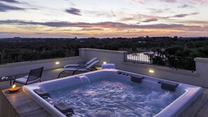 Un jacuzzi en una terraza con sillones reclinables y vistas al paisaje.