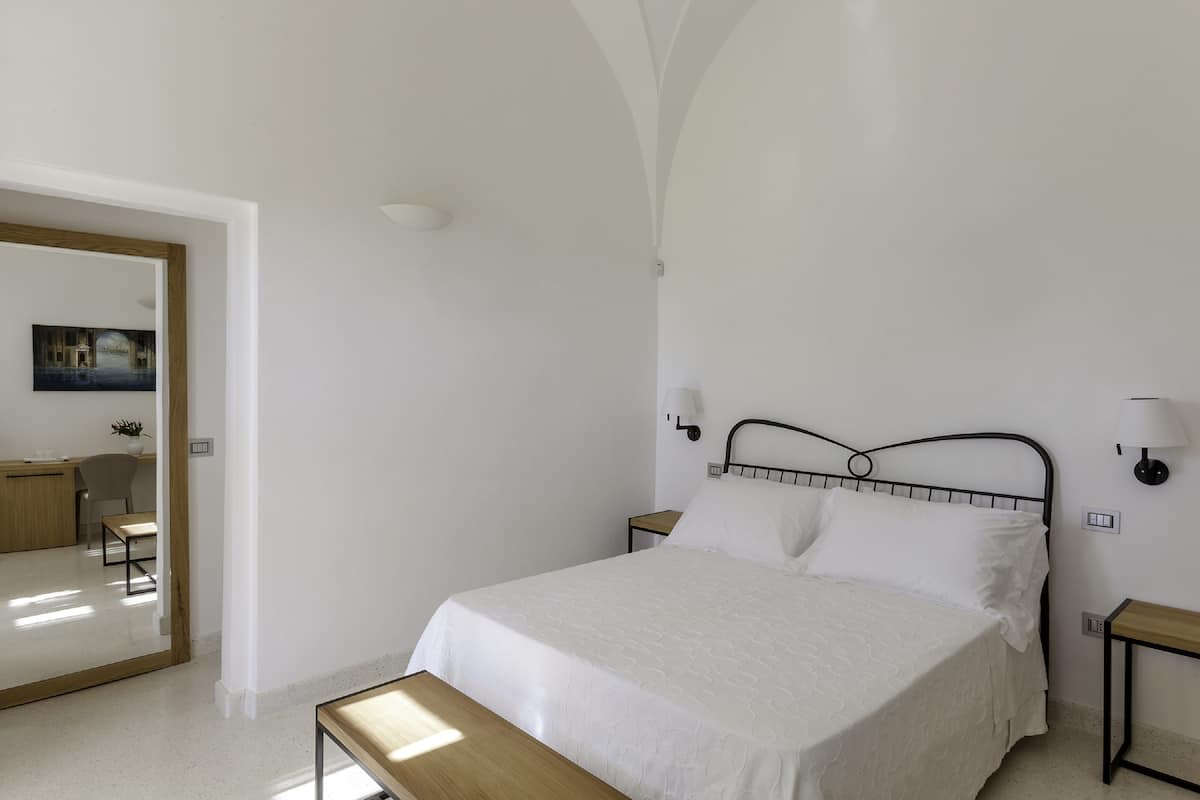 A bedroom with a bed, bedside tables, and a mirror.
