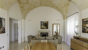 Amplia sala de estar con techo abovedado, chimenea, un conjunto de sofá, una mesa de comedor con sillas y un mueble de madera.