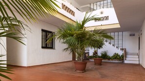 A spacious courtyard with terracotta tiled flooring, potted plants, and a staircase leading to an upper level. - Crown Resorts Club Calahonda (Mijas)