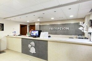 A reception area with a reception desk, a computer monitor, and a sign that reads "RECEPCION".