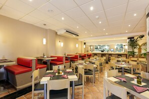 A restaurant with booths and tables, a bar area, and a kitchen in the background.