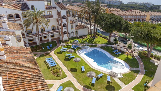 A resort with a swimming pool, sun loungers, palm trees, and a view of the sea. - Crown Resorts Club Calahonda (Mijas)
