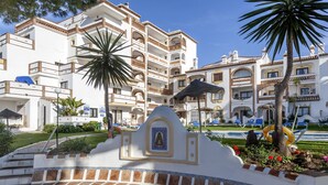 A courtyard with a pool, palm trees, and a building with balconies. - Crown Resorts Club Calahonda (Mijas)