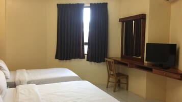 A hotel room with two beds, a desk with a chair, a television, and an air conditioning unit.