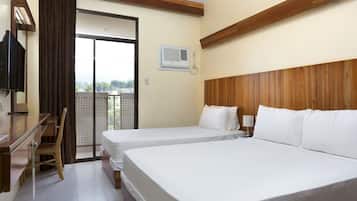 A hotel room with two beds, a desk, a chair, an air conditioning unit, and a view through a sliding door.