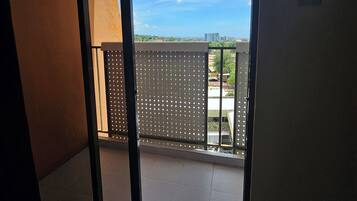 A room with a sliding glass door leading to a balcony with a view of the sky and buildings.