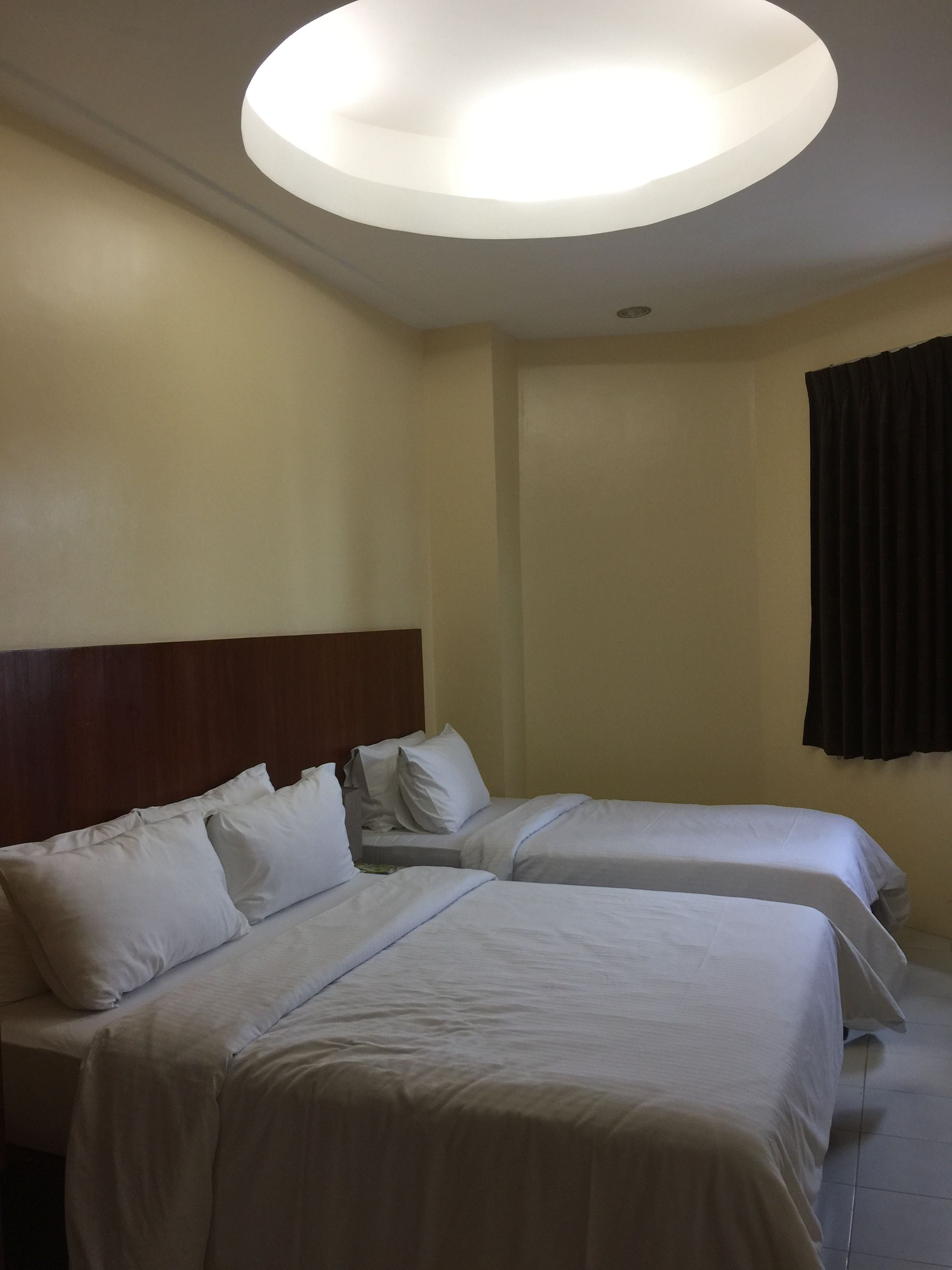 A hotel room with two beds, a wooden headboard, and a ceiling light fixture.