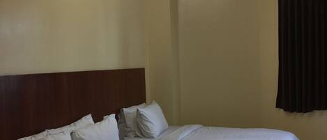 A hotel room with two beds, a wooden headboard, and a ceiling light fixture.