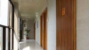 A hallway with a tiled floor, wooden doors, and a potted plant. - Tsai Hotel and Residences (Cebu City)