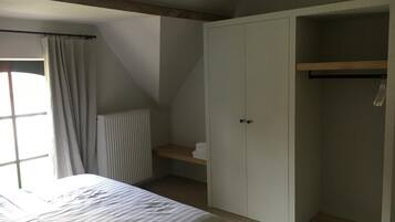 A bedroom with a bed, a wardrobe, a radiator, and a window with curtains.