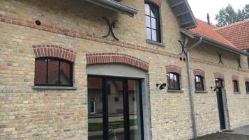 Een gebouw van baksteen met boogvensters en een glazen deuropening.