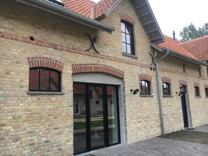 A brick building with arched windows and a glass door entrance. - Groot Noordhof (Nieuwpoort)