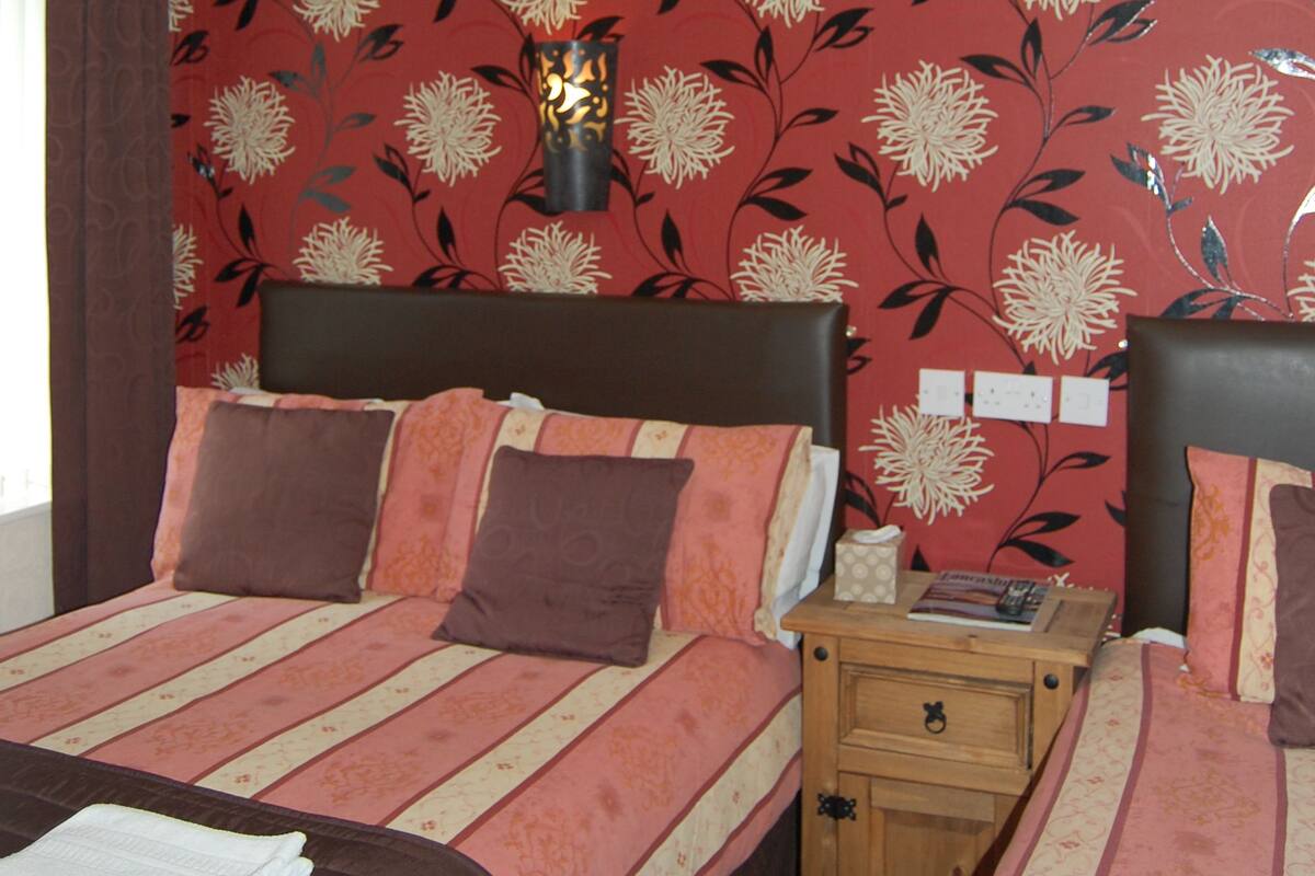 A hotel room with a large bed, a bedside table, and a nightstand.