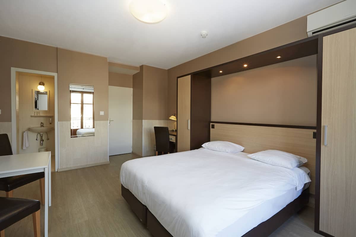 Ett hotellrum med en säng, ett skrivbord och en stol.