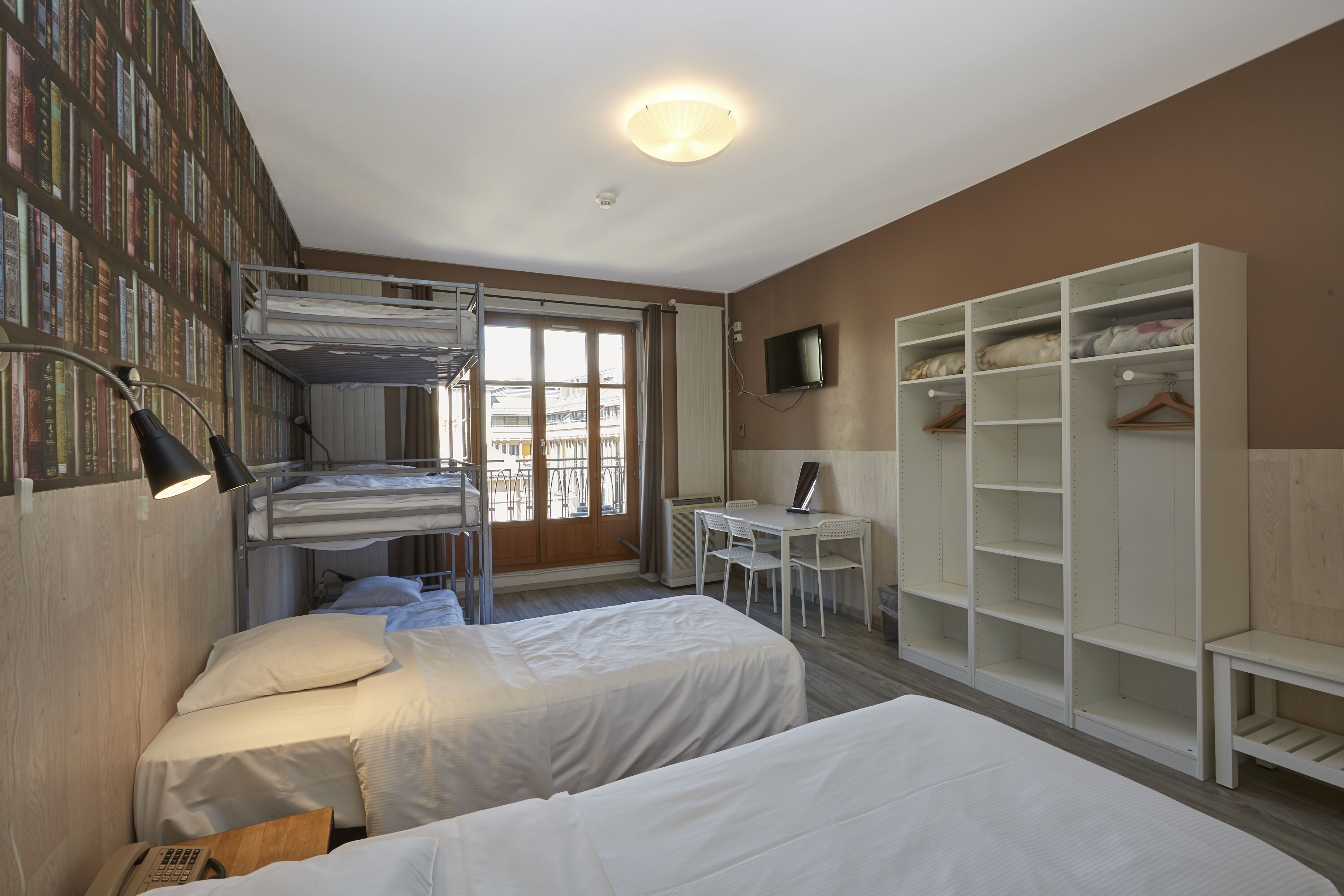 Una habitación con literas, un escritorio, una silla, un televisor y un armario.