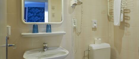 A bathroom with a sink, mirror, toilet, towel rack, and a hairdryer.