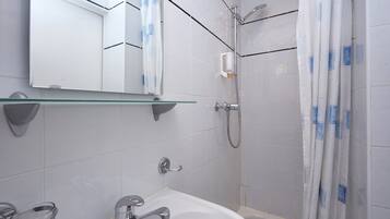 A modern bathroom with a glass shelf, a sink, a shower, and a toilet.